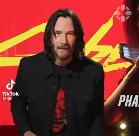 a man with long hair and a beard is standing in front of a red background and looking at the camera .