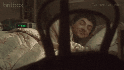 a man is sleeping in a bed with a clock that says 7:37