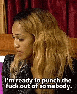 a woman is sitting on a couch and saying `` i 'm ready to punch the fuck out of somebody .