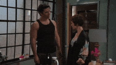 a man in a tank top stands next to a woman in a kimono
