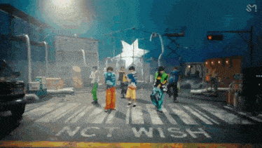 a group of people are dancing on a street with the words nct wish painted on the sidewalk