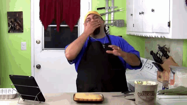 a man in an apron is covering his mouth in front of a container that says country girl