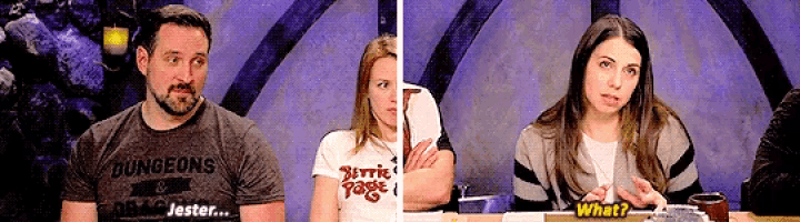 a man and a woman are sitting at a table and the man is wearing a shirt that says dungeons and jester