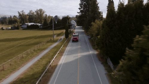 an aerial view of a road with a red truck driving down it