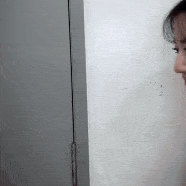 a woman is standing next to a door and looking at something .