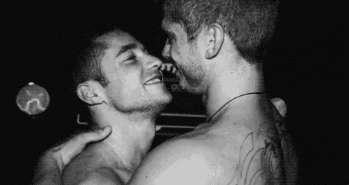 a black and white photo of two men hugging each other .