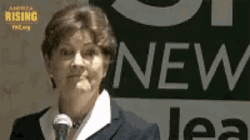 a woman stands in front of a microphone in front of a sign that says new lea
