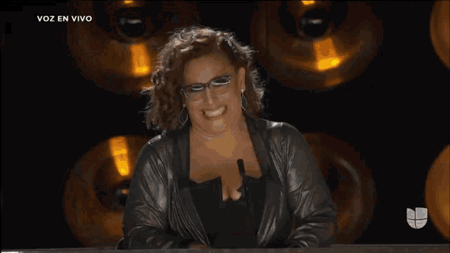 a woman is smiling in front of a microphone and the words voz en vivo are on the bottom right