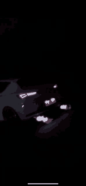 a white car is parked in the dark with its tail light on
