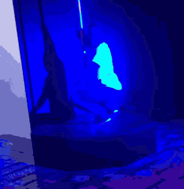 a blue light is shining on a statue of a person in a dark room .
