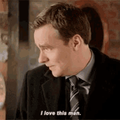 a man in a suit and tie is talking and saying `` i love this man '' .