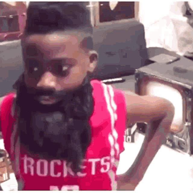 a young boy with a beard wearing a rockets jersey