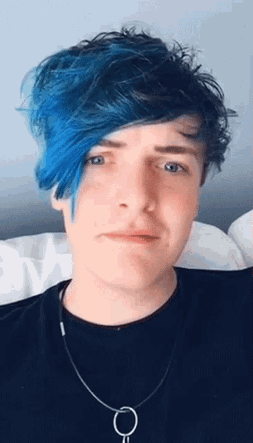 a young man with blue hair is wearing a necklace