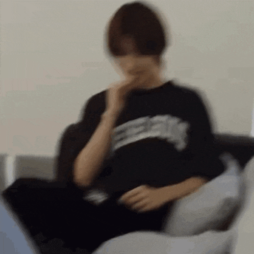 a blurry picture of a man sitting on a couch .