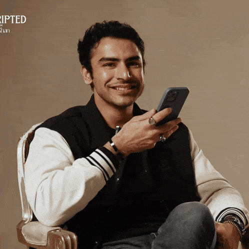 a man sitting in a chair holding a cell phone with the word ripped on the bottom right