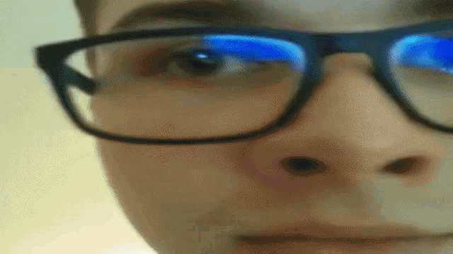 a close up of a person 's face wearing glasses with blue lenses