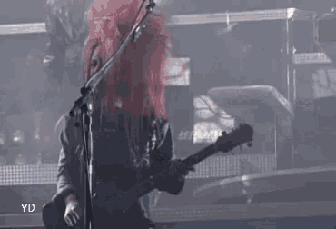a person with red hair is playing a guitar on stage .