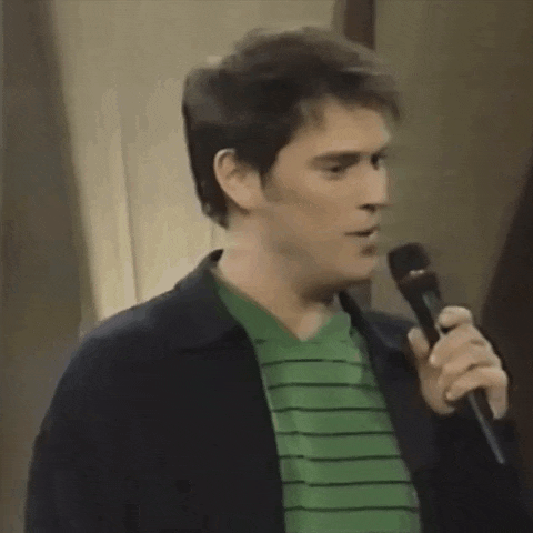 a man in a green striped shirt is holding a microphone and talking into it .