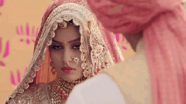 a bride and groom are posing for a picture . the bride is wearing a veil and a turban .