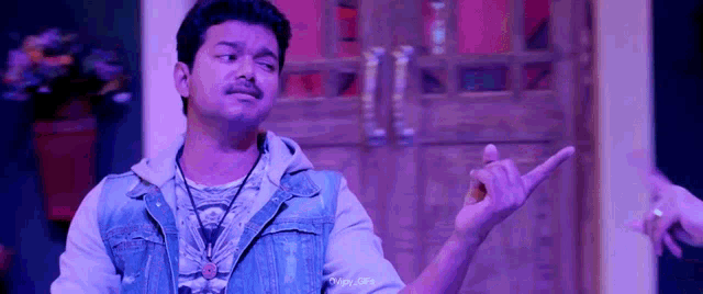 a man in a denim jacket is pointing at something with his finger