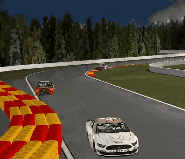 a mustang race car is driving down a track