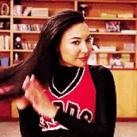 a woman in a cheerleader uniform is brushing her hair in a room .