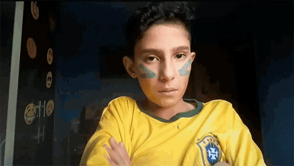 a young boy wearing a yellow shirt with a brazilian flag on it