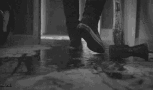a black and white photo of a person standing next to a bloody hammer .