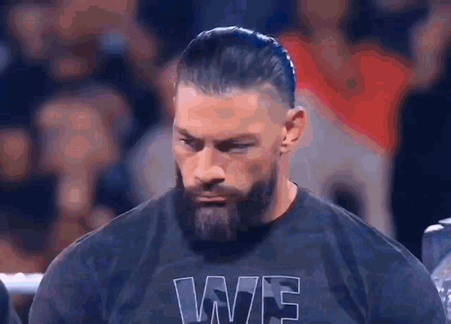 a man with a beard is wearing a black t-shirt with the word we on it .