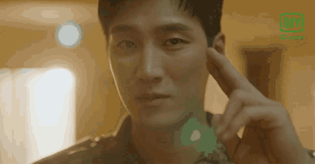 a close up of a man covering his ears with his finger and a ioi logo in the background