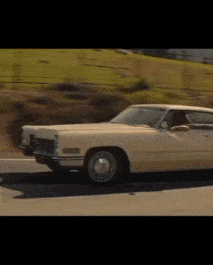 a white cadillac is driving down the road