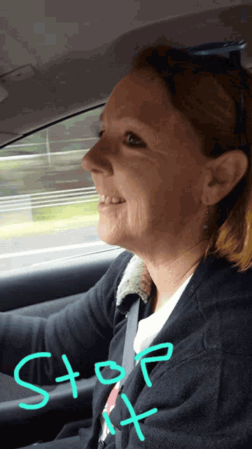 a woman is driving a car with the word stop written on the side