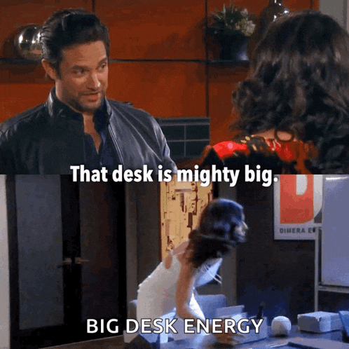 a man and a woman are standing in front of a sign that says big desk energy