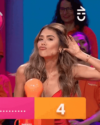 a woman in a red dress holds her hand to her ear behind a sign that says 4