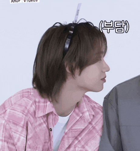 a man wearing a pink plaid shirt and a black headband has a sticker on his hair that says ahuf videos