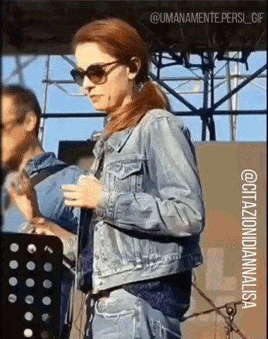 a woman wearing sunglasses and a denim jacket is standing on a stage