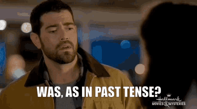 a man with a beard is talking to a woman and says " was , as in past tense "