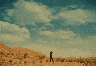 a silhouette of a person walking in front of a sunset