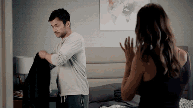 a man and woman are standing in a bedroom with a map of the world on the wall