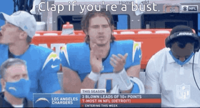 a man in a los angeles chargers jersey applauds