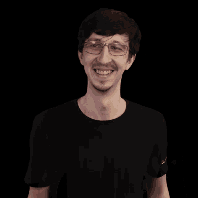 a man wearing glasses and a black shirt is giving two thumbs up