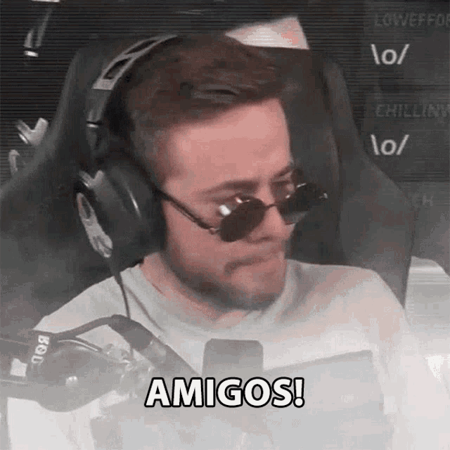 a man wearing headphones and sunglasses is sitting in a chair .