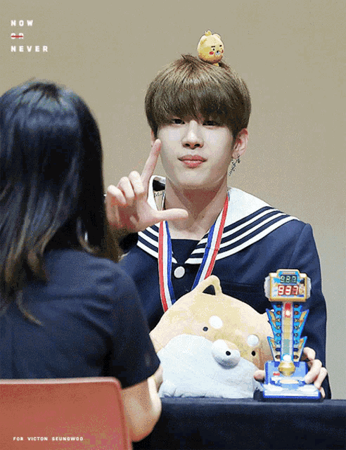 a young man with a medal around his neck is holding a stuffed animal and a prize that says ' 8888 '