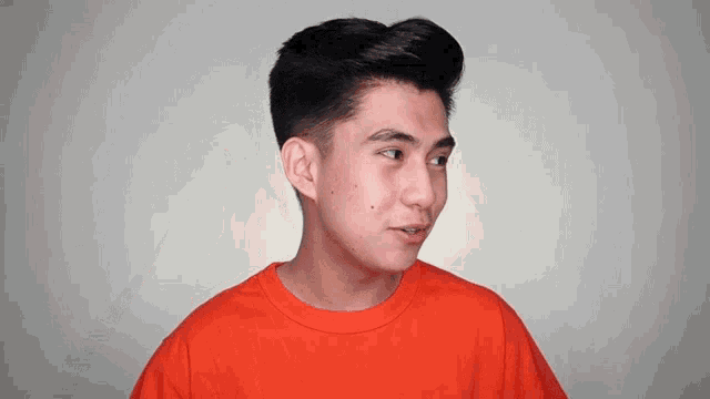 a young man wearing an orange shirt is looking to the side
