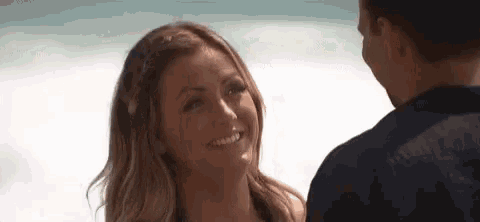 a woman is smiling at a man on the beach .