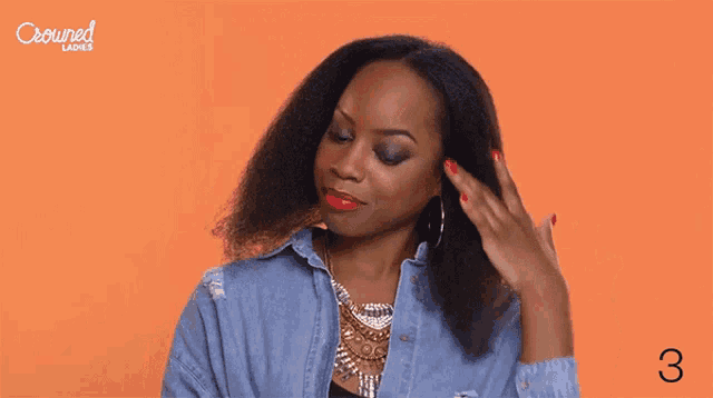a woman in a denim shirt is holding her hair in front of an orange background with the number 3 on it