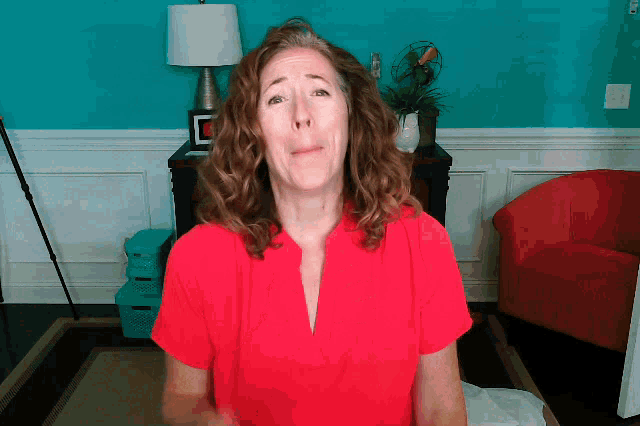 a woman in a red shirt is sitting in front of a blue wall