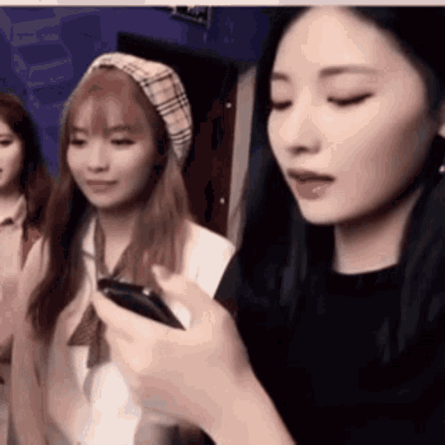 a group of young women are standing next to each other looking at their phones .