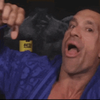 a man in a blue jacket is making a funny face with his hand in front of his face .