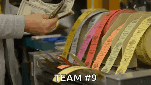 a person is counting money in front of rolls of tickets that say team 9